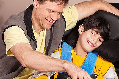 Boy with a disability in a wheelchair playing checkers with father at home