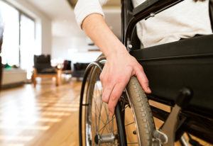 Young woman with a disability in wheelchair at home in living room.